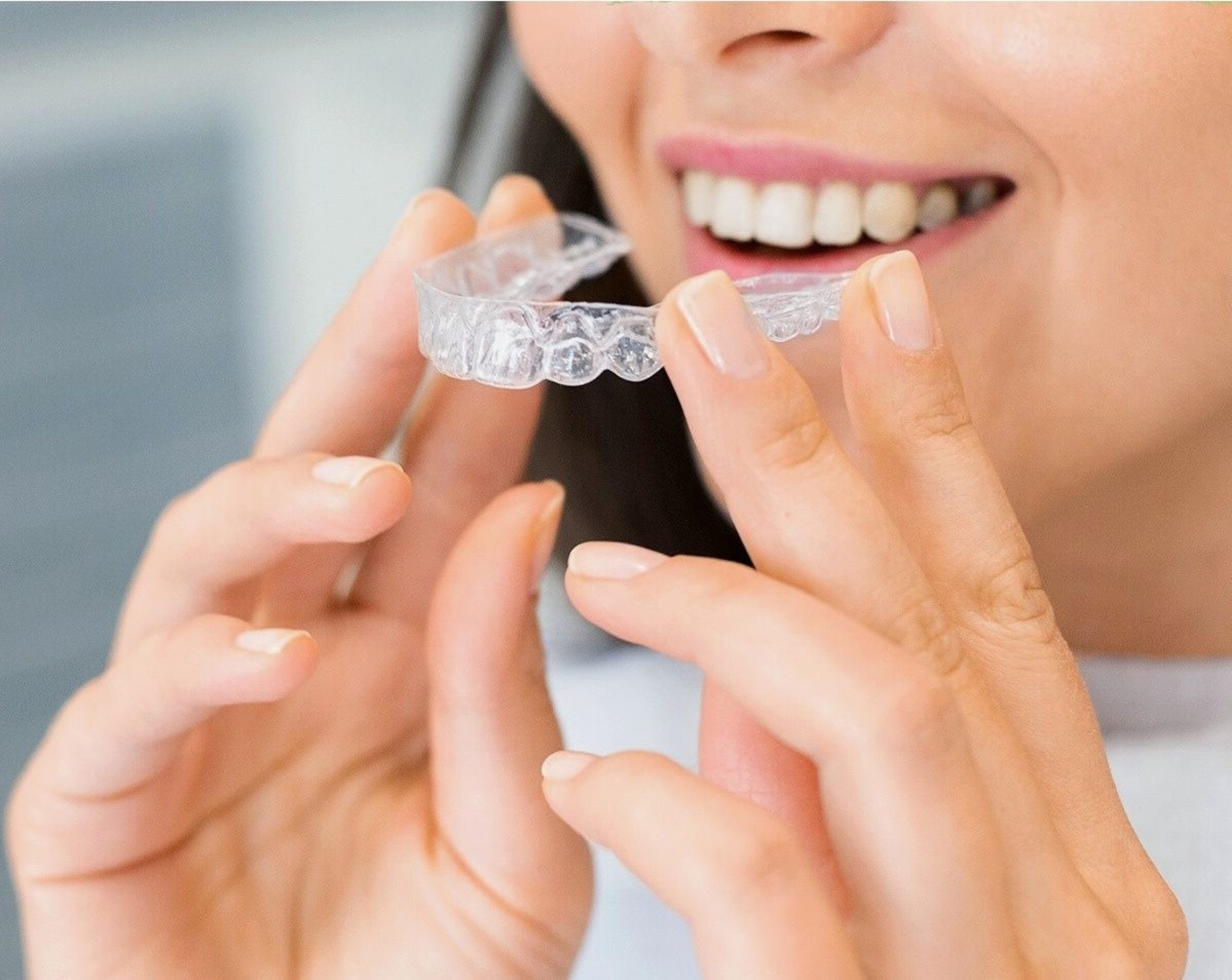 A woman in the motion of inserting her Invisalign.