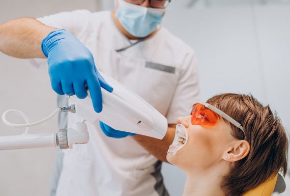 A denist doing a teeth whitening procedure on a child patient.